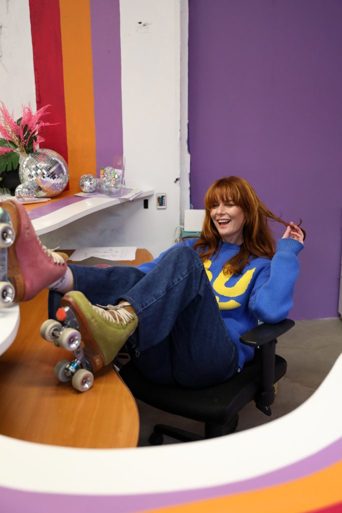 RollerMart owner, Stacey Skates, sitting at the funky front desk at the private roller skate studio in Sydney.